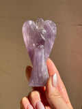 Hand-carved lavender amethyst angel held up in the sunlight
