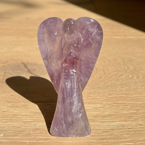 Amethyst angel standing on a light oak table in the sun