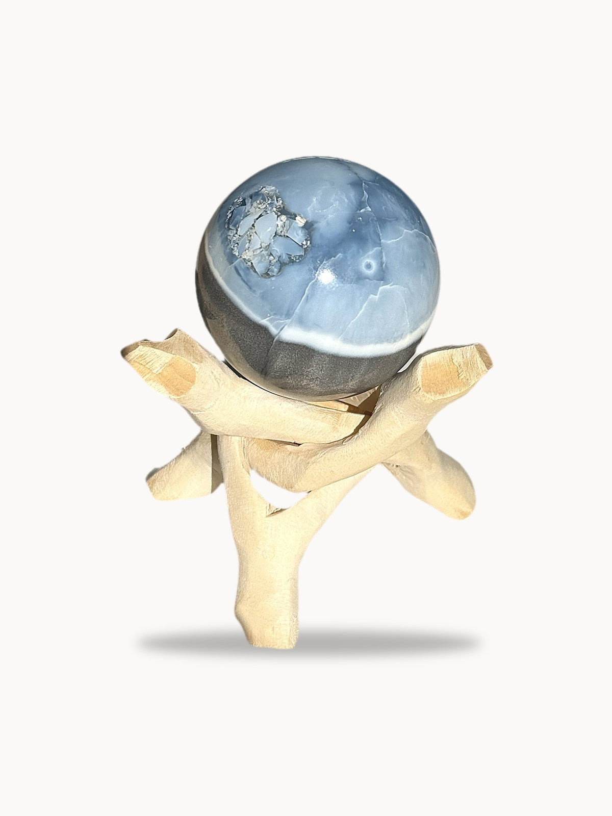 Large blue opal sphere with a crystal pocket on a wooden stand