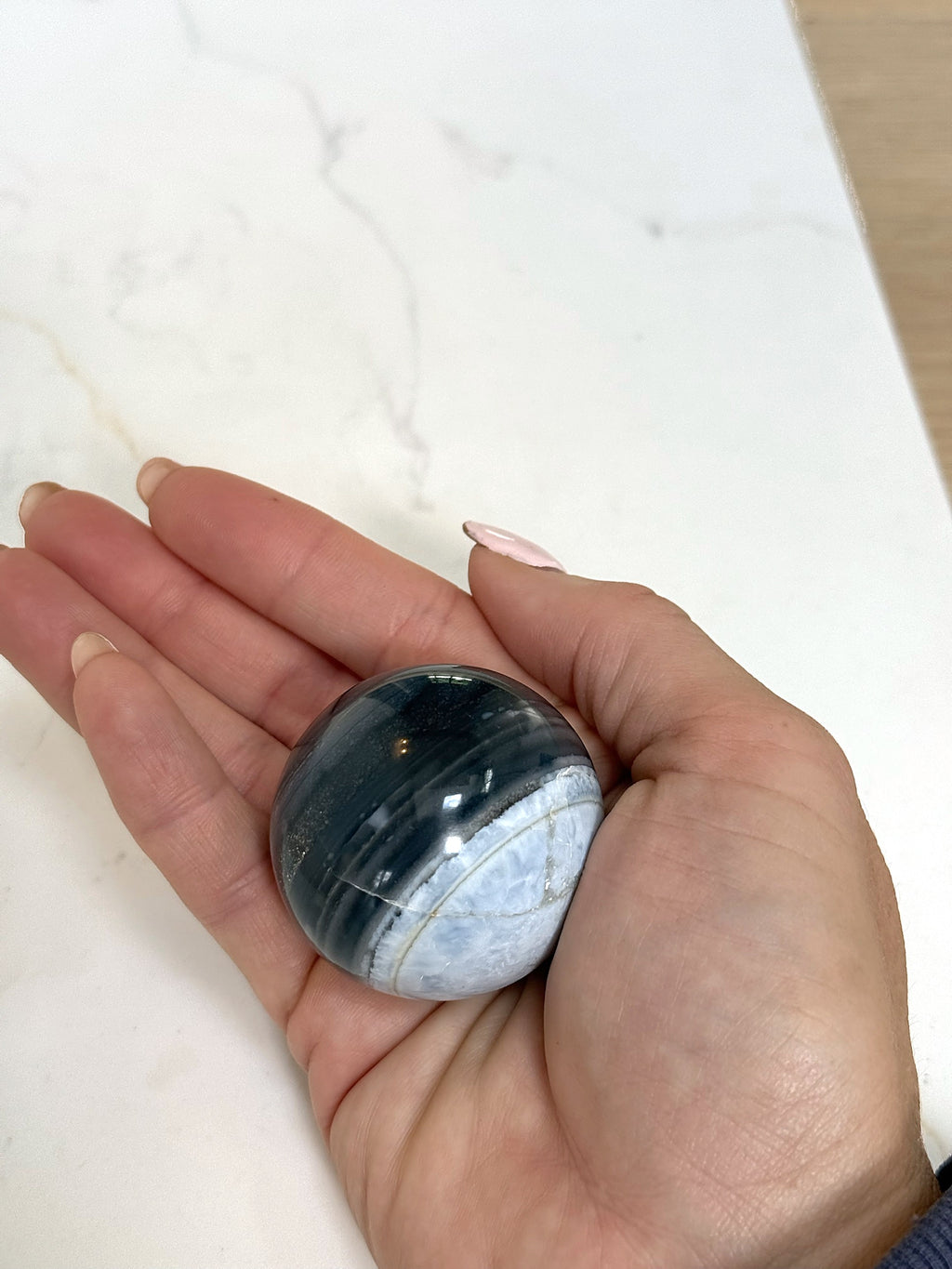 Medium blue opal sphere held in the palm