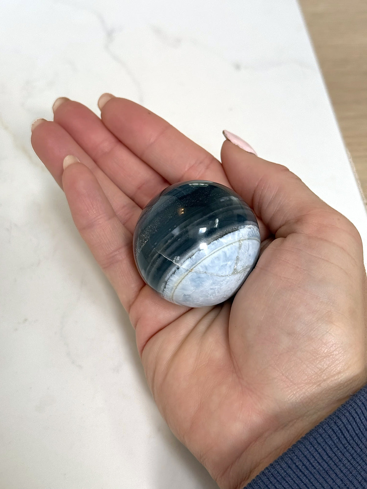 Medium blue opal sphere, pale blue side, in the hand