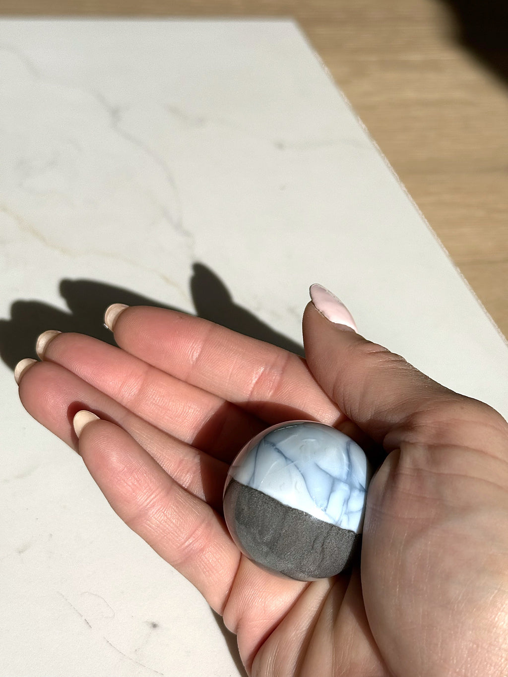 Small blue opal sphere held in the hand