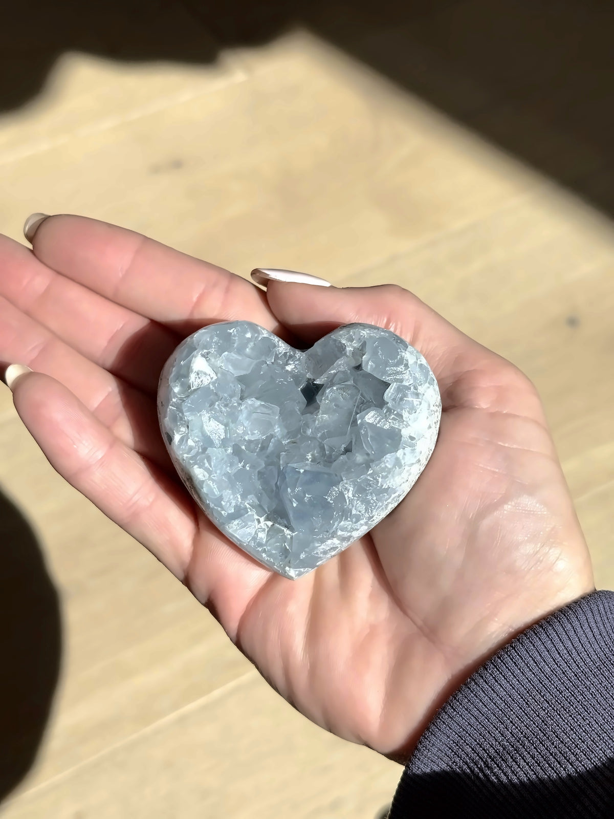 Celestite heart with pale blue crystals, held in the palm