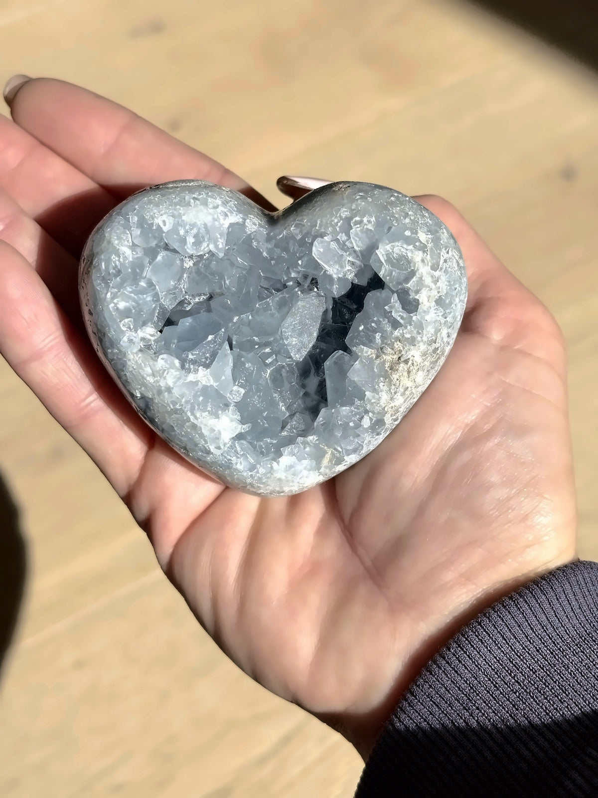 A second celestite heart with a deep crystal pocket, held in the palm