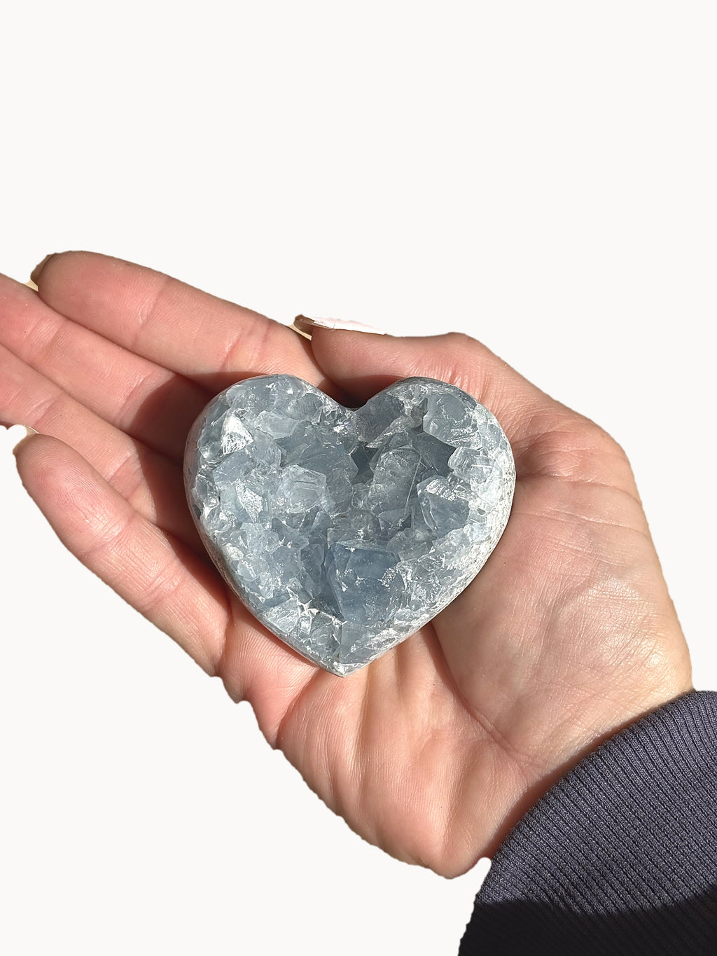 Small celestite heart with pale blue crystals, held in the palm