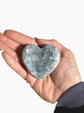 Small celestite heart with pale blue crystals, held in the palm