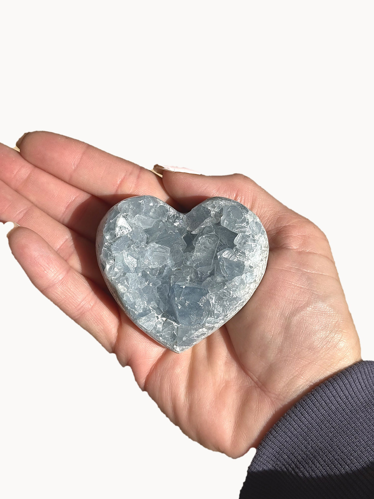 Small celestite heart with pale blue crystals, held in the palm