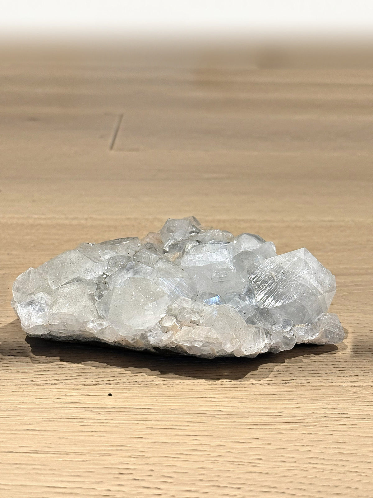 Clear apophyllite cluster on a wooden floor