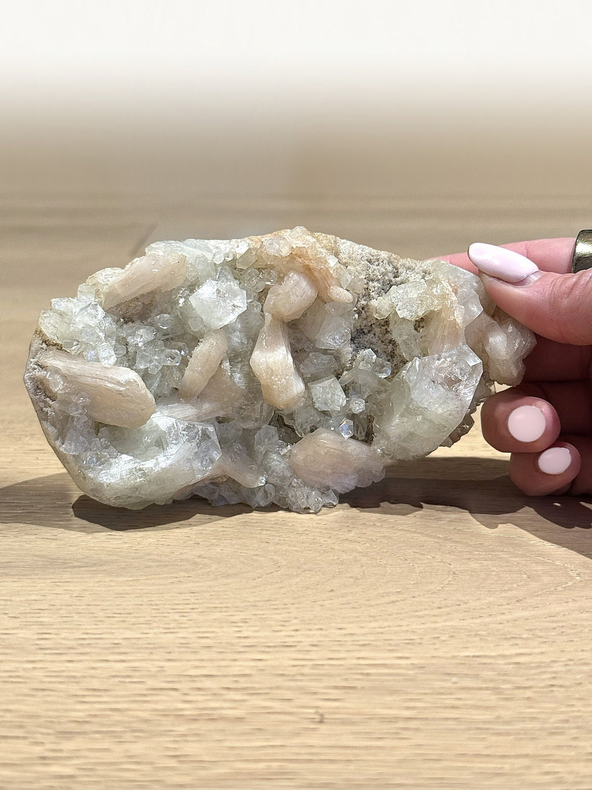 Green apophyllite with peach stilbite blades, held to show its size