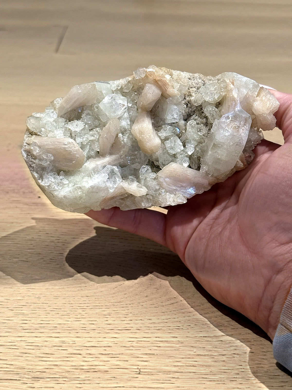 The green apophyllite and stilbite cluster resting in the palm