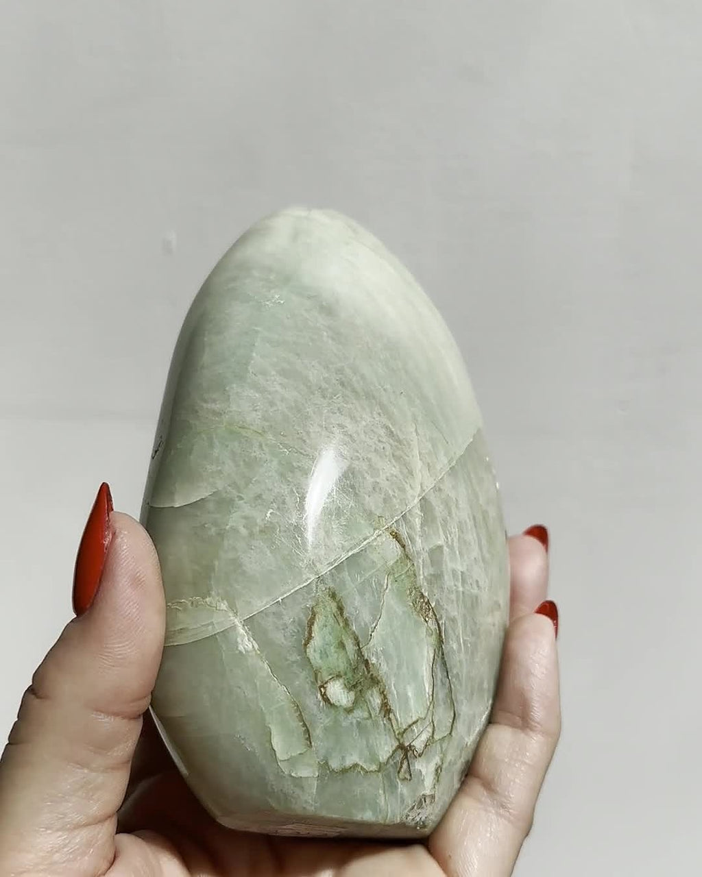 Green moonstone dome held in the hand