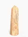 Polished peach moonstone tower, 8 inches tall, with gray veins and a gold band near the tip