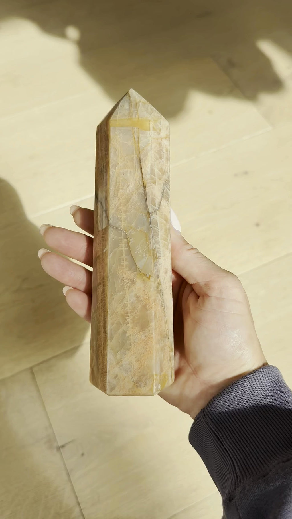 Peach moonstone tower turning in the hand in sunlight