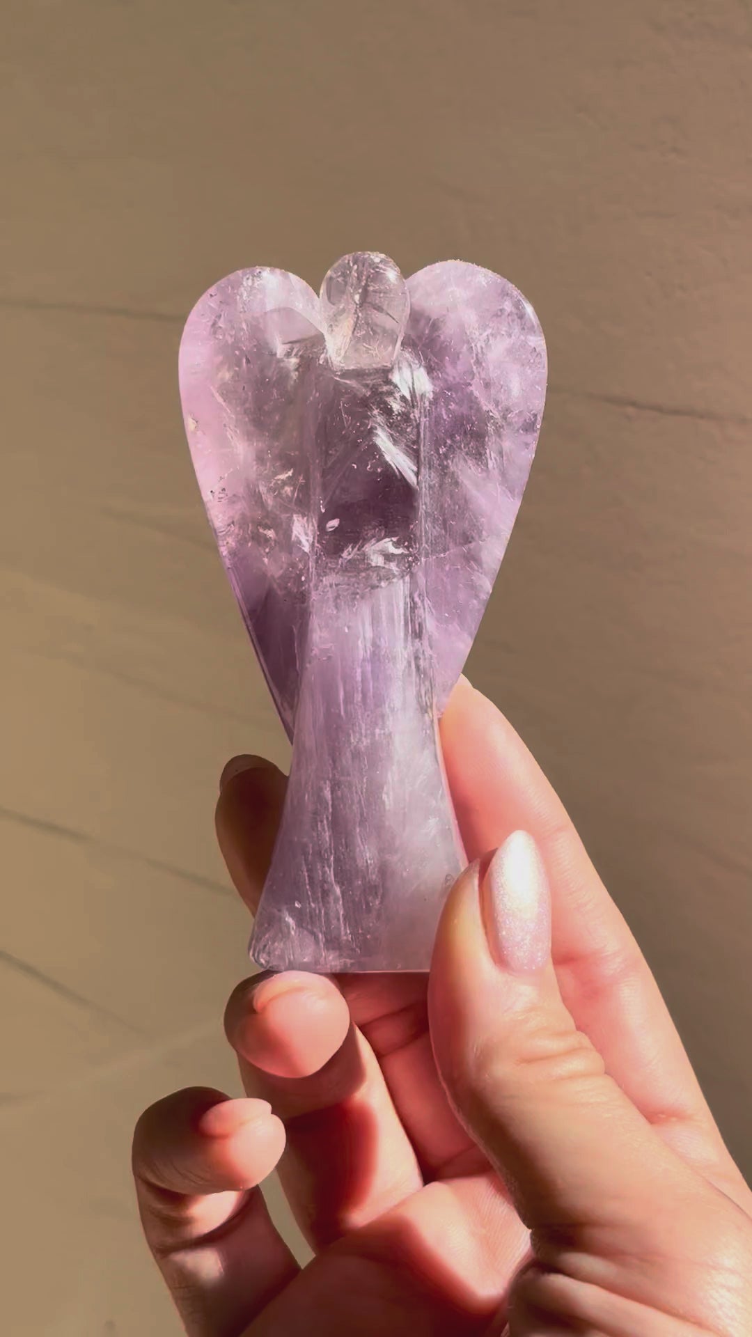 Amethyst angel turning in the hand in sunlight