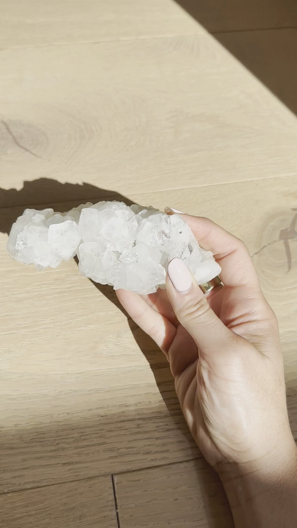 The sculptural apophyllite cluster turned in the hand in sunlight