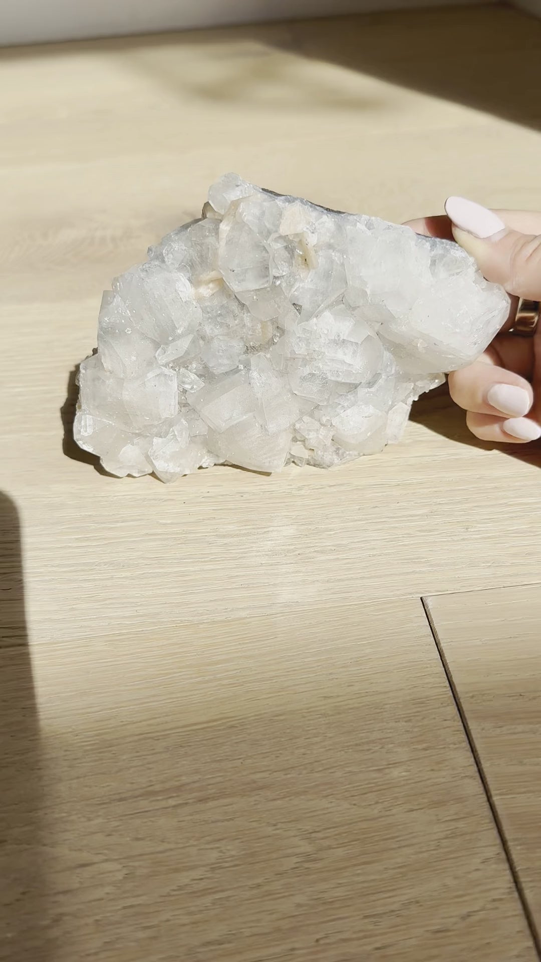 The clear apophyllite cluster turned in the hand in sunlight