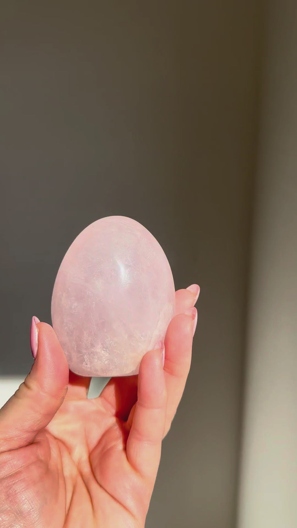 Rose quartz dome turning in the sunlight in a hand, Rising Star Crystals