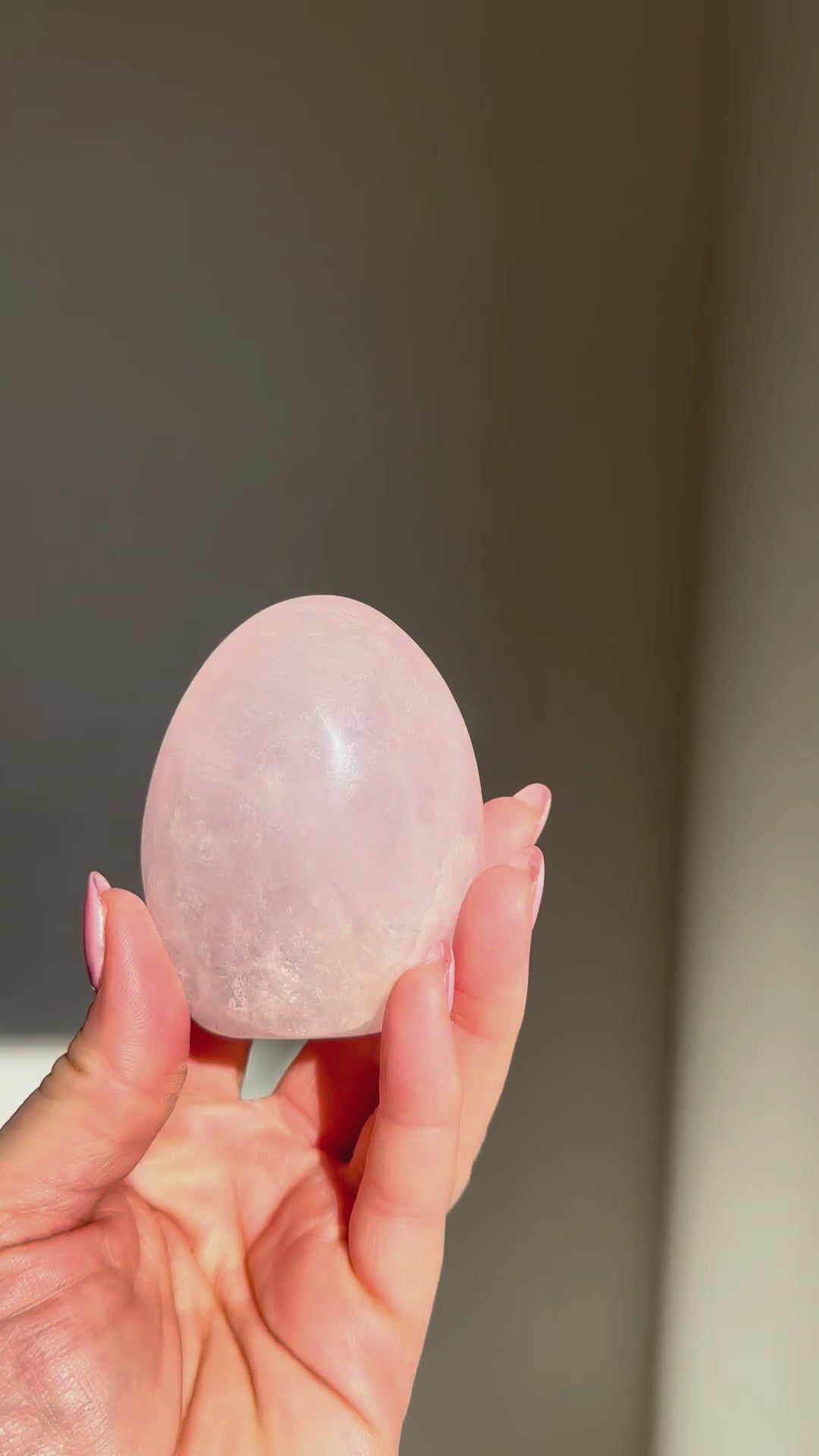 Rose quartz dome turning in the sunlight in a hand, Rising Star Crystals