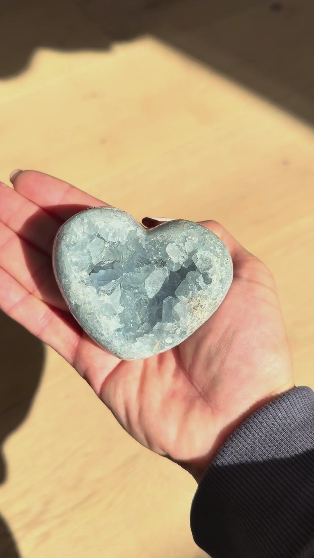 Small celestite heart turning in the hand in sunlight