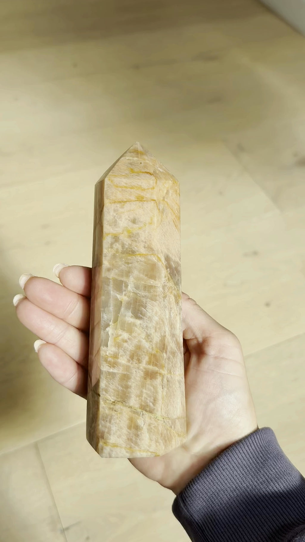 Peach moonstone tower turning in the hand in sunlight