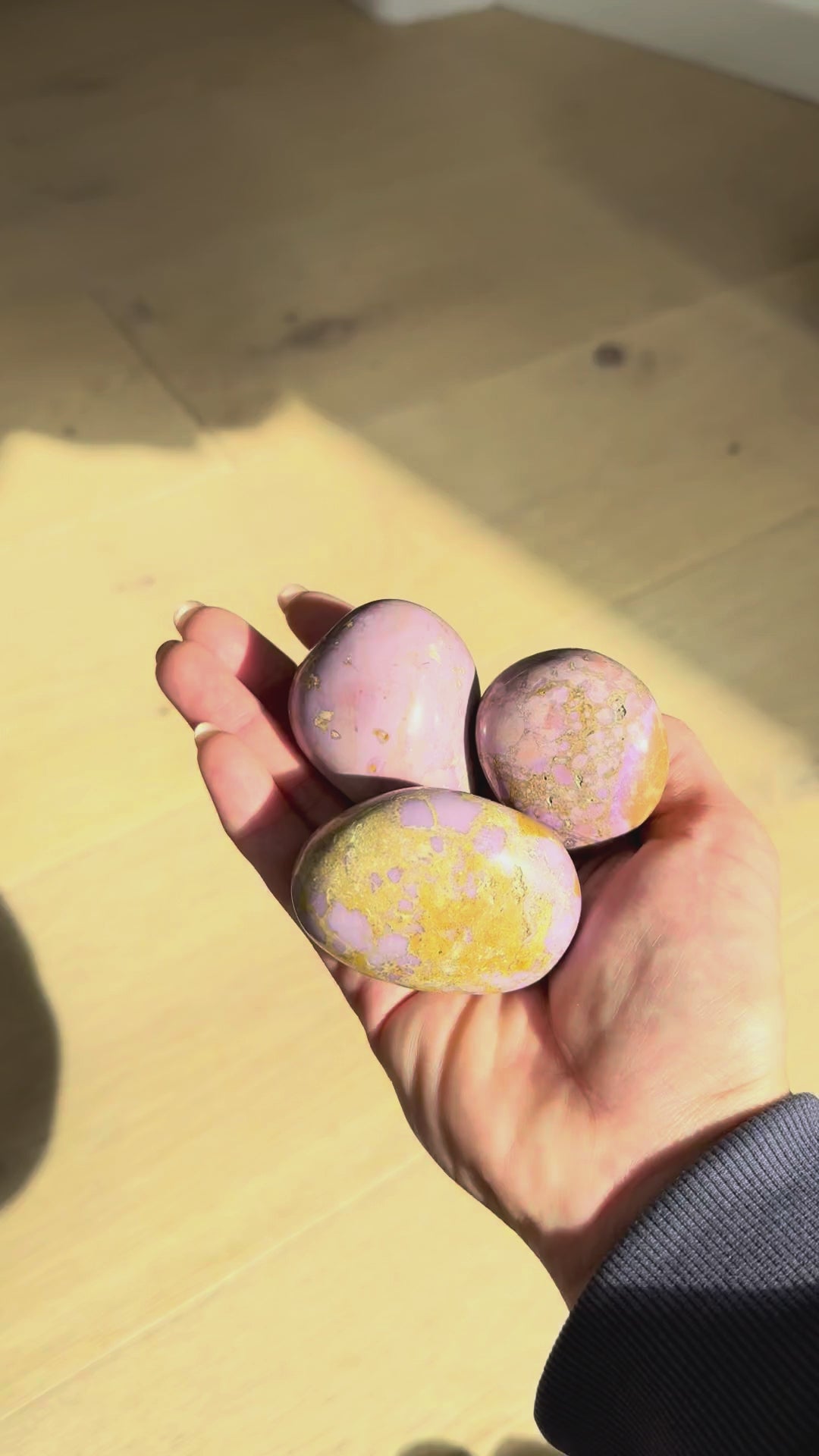 Phosphosiderite meditation stones turning in the hand in sunlight