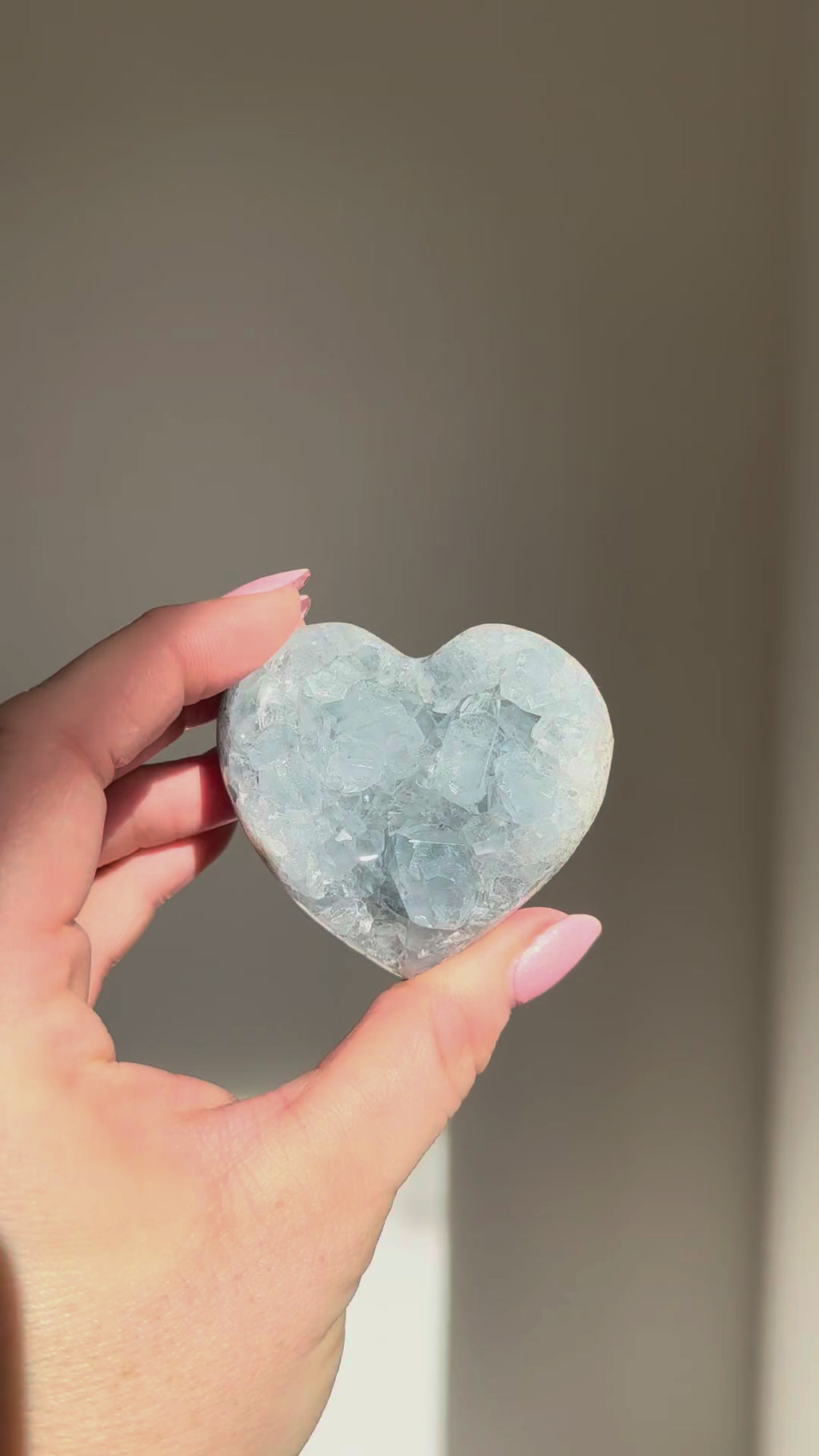 Small celestite heart turning in the sunlight in a hand