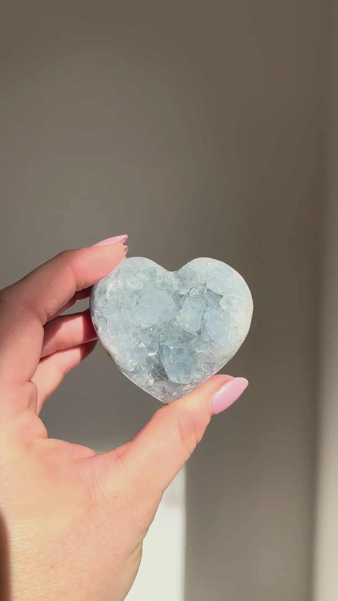 Small celestite heart turning in the sunlight in a hand