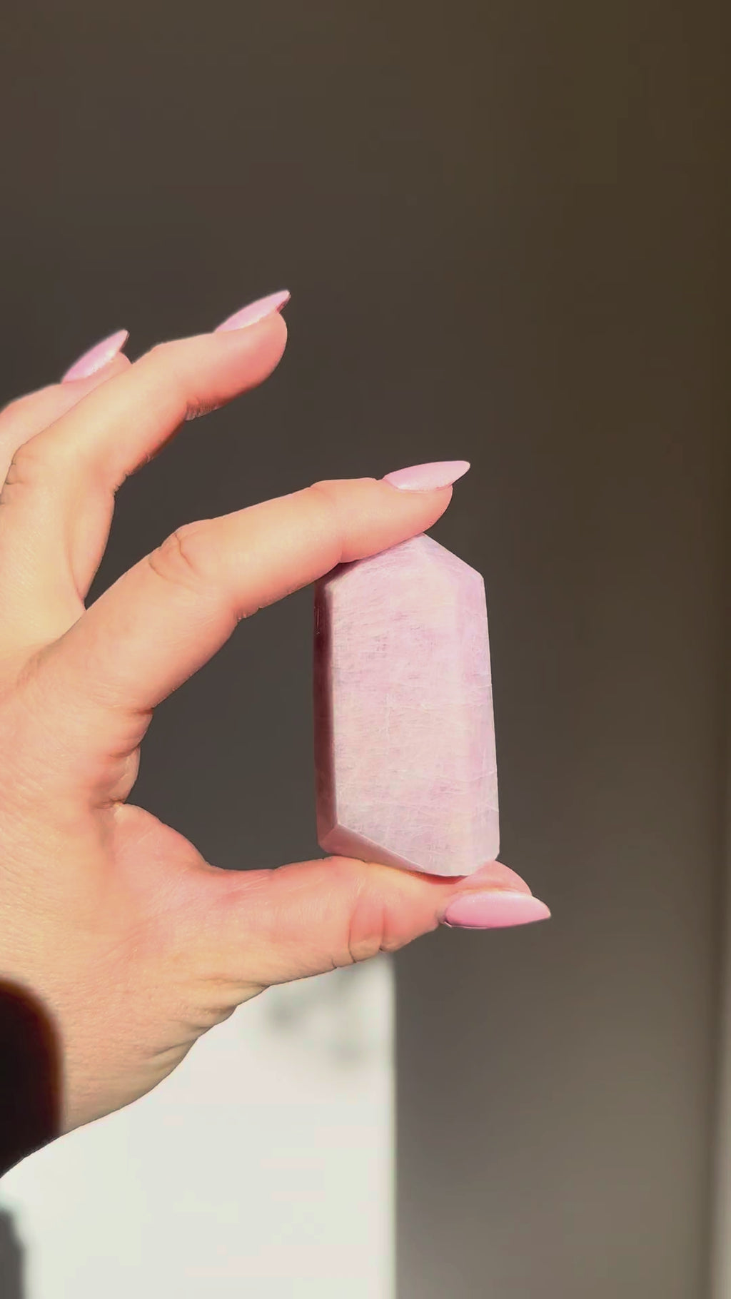 Kunzite point turning in the sunlight in a hand, Rising Star Crystals
