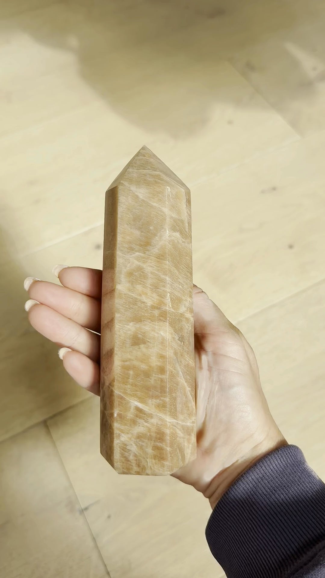Peach moonstone tower turning in the hand in sunlight