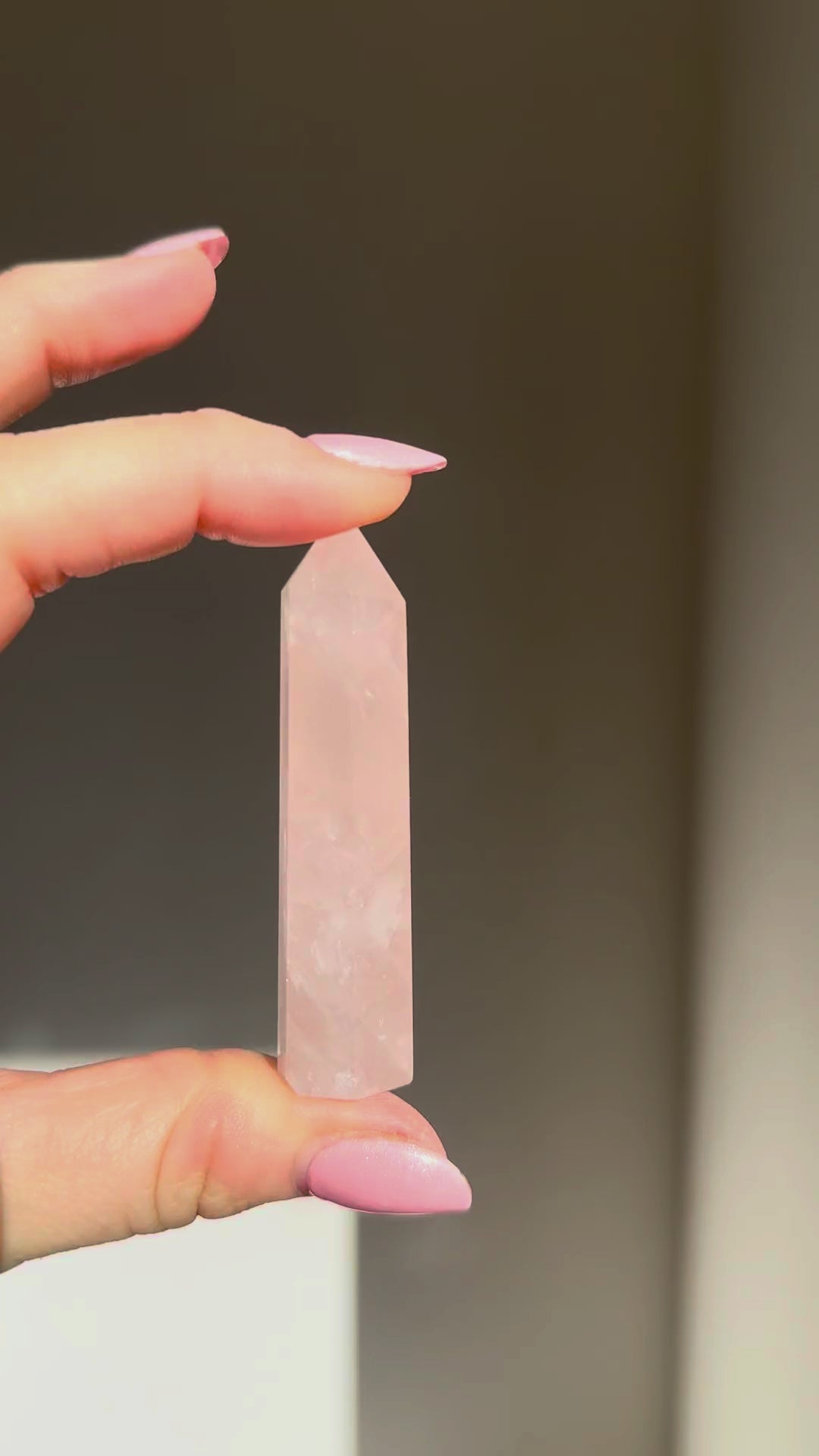 Rose quartz point turning in the sunlight in a hand