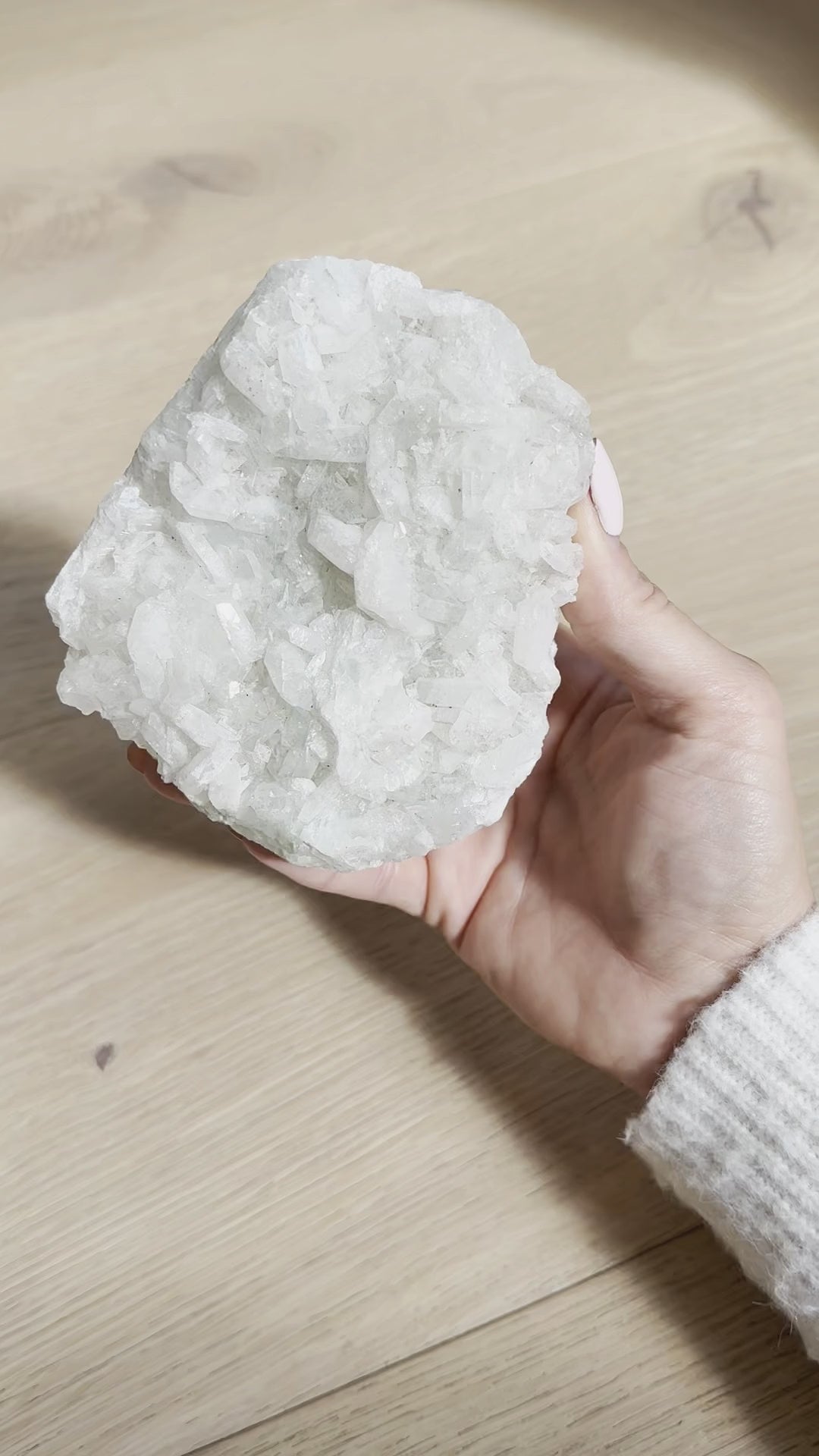 The snow-white apophyllite cluster turned in the hand in sunlight