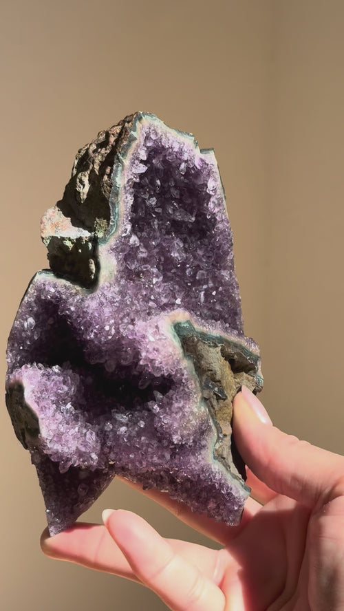 Amethyst cluster turning in the hand in sunlight
