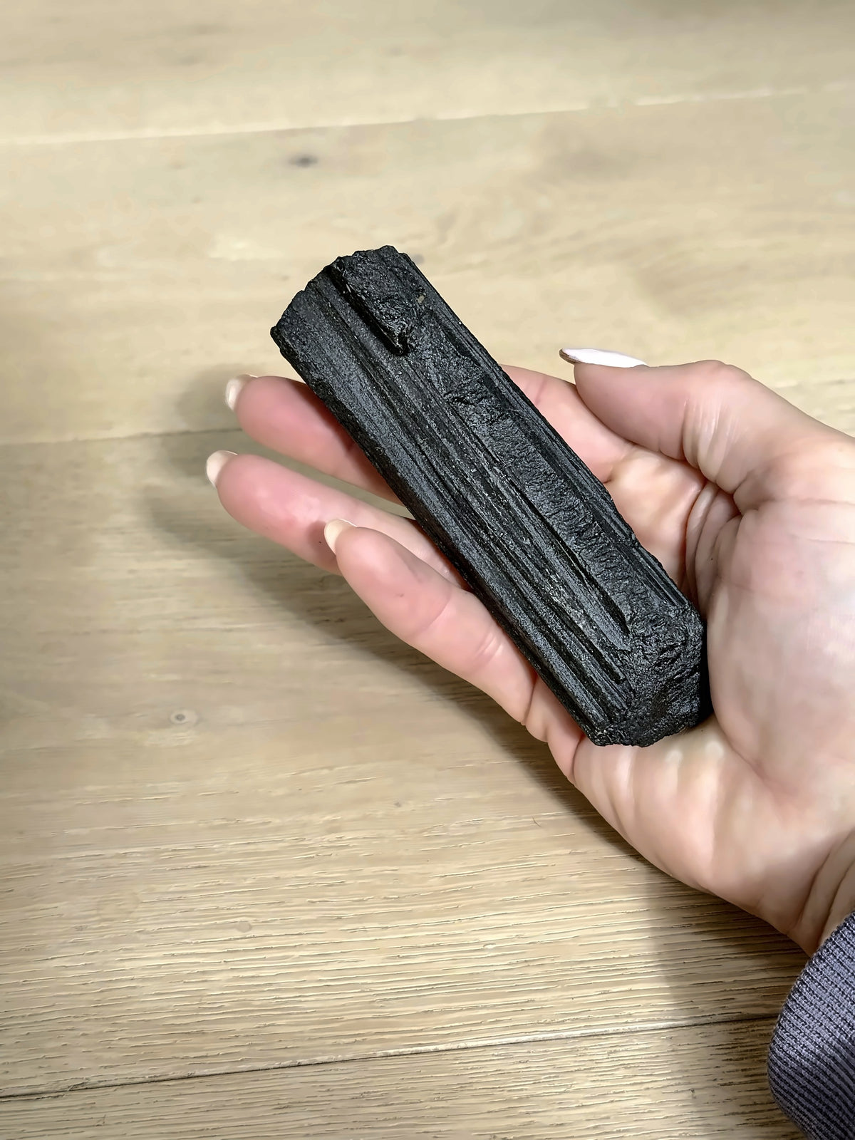 Raw black tourmaline wand in hand