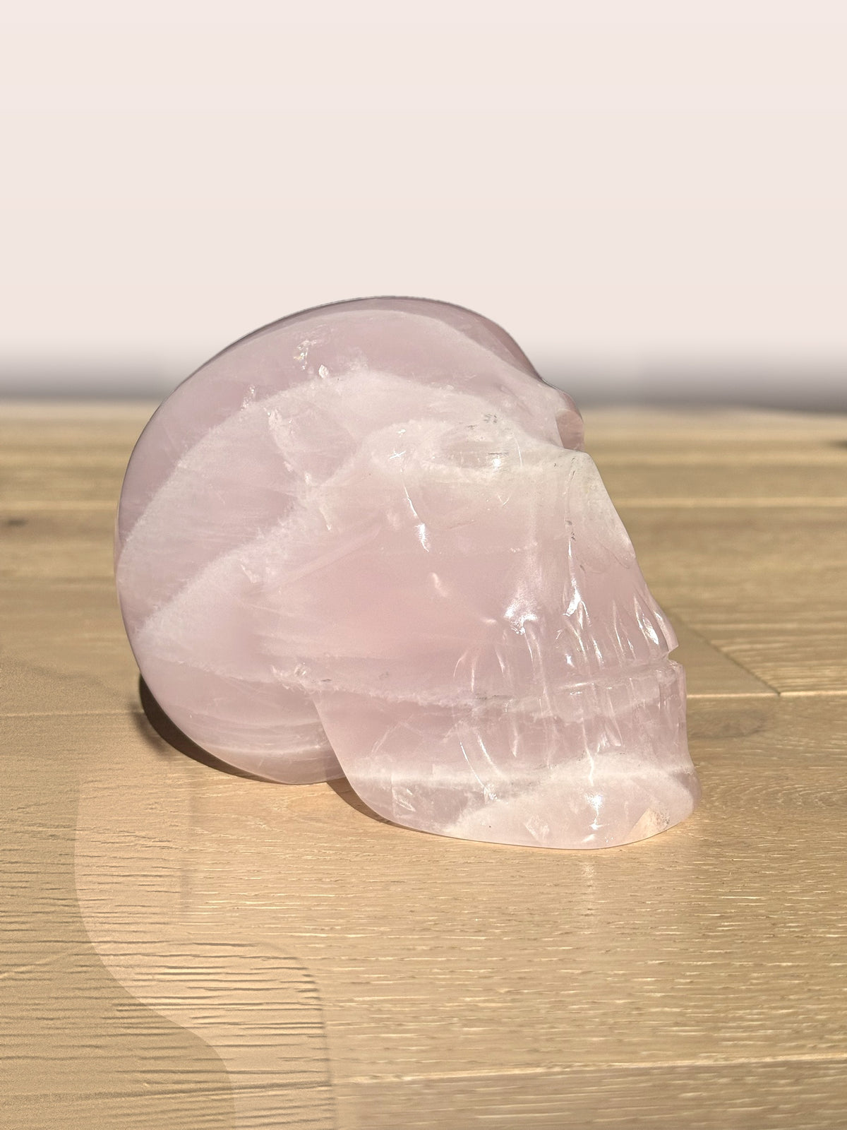 Large rose quartz skull with white banding, side view in sunlight