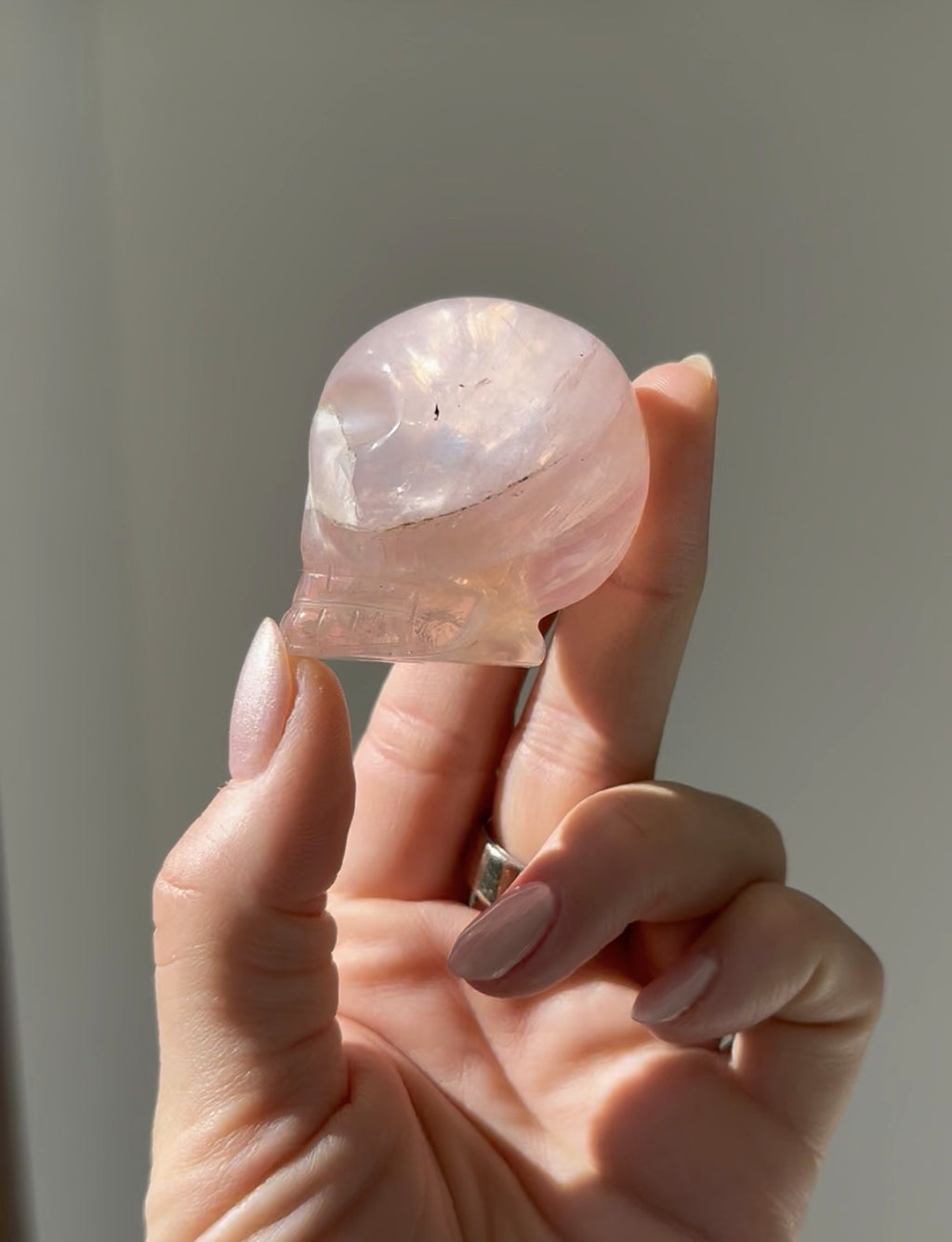 Small rose quartz skull glowing in the sunlight, held in hand