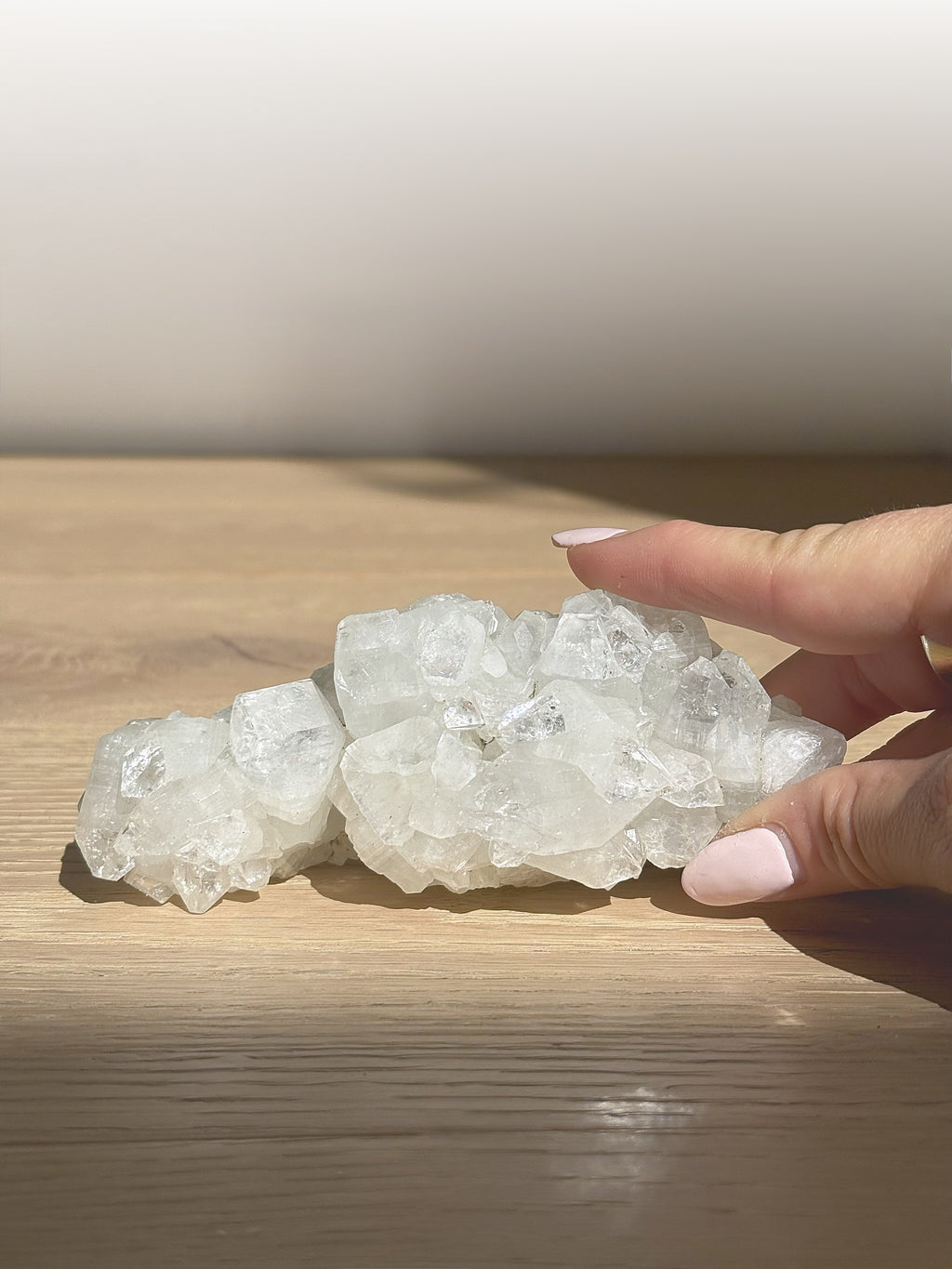 Sculptural clear apophyllite cluster resting on a wooden table
