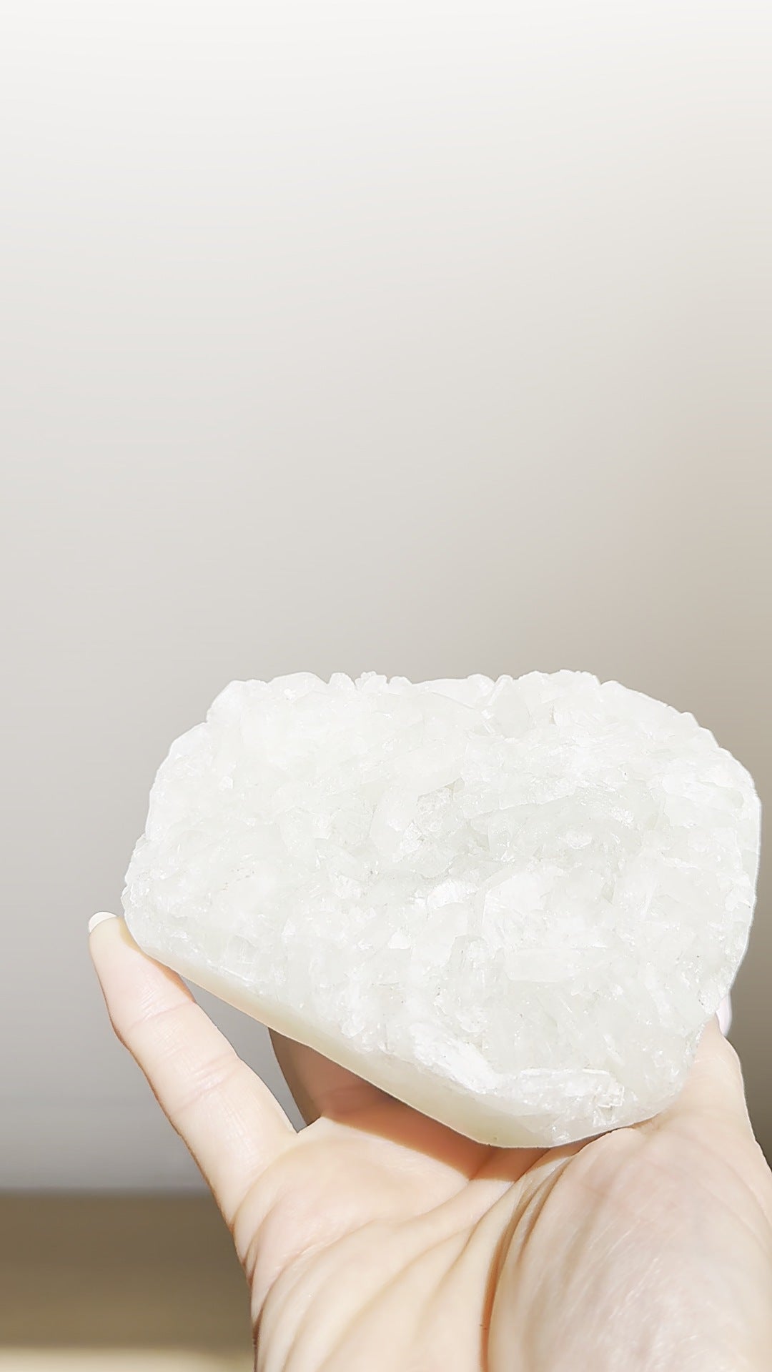 The snow-white apophyllite plate held up to show its frosted crystals